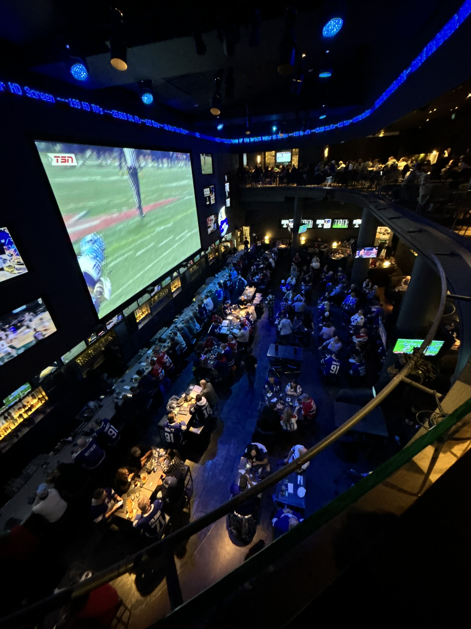 Fans dining at Real Sports beneath a giant screen showing a hockey broadcast.